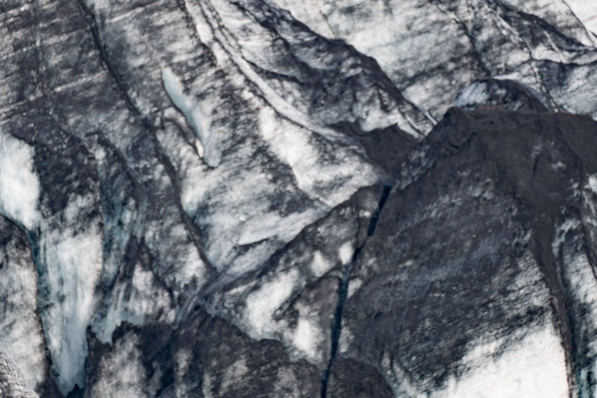 A raft floats a braided channel with the blue face of Matanuska Glacier still visible upstream.