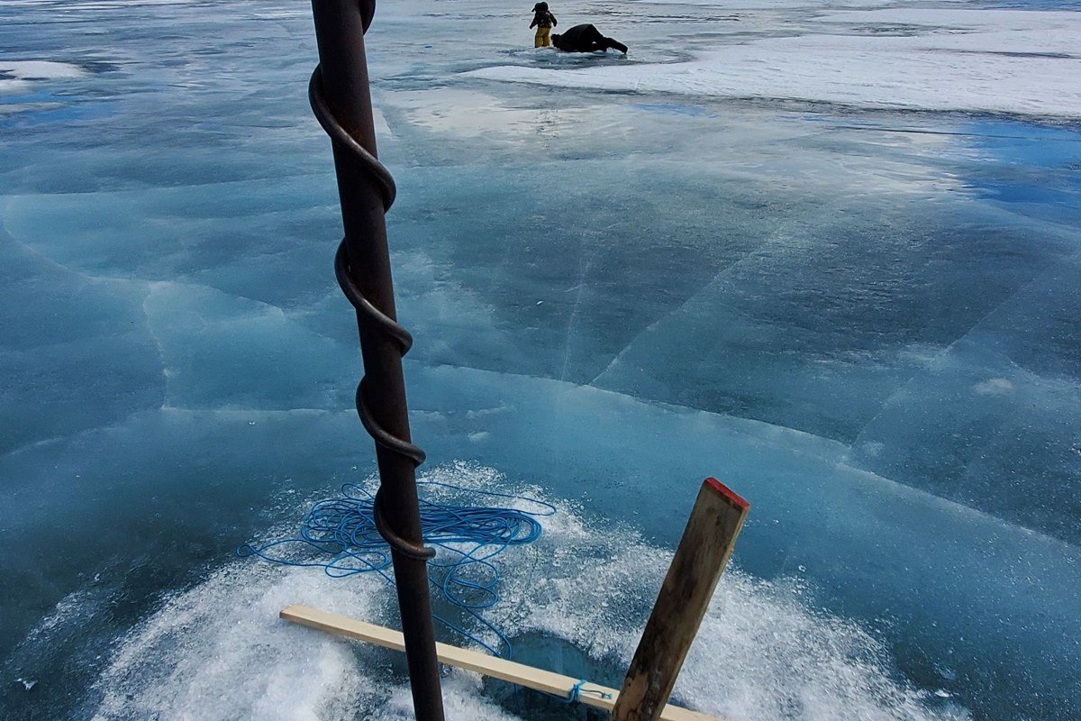 A raft crosses the open, wind-rippled water of Tazlina Lake with the distant Tazlina Glacier ice field visible on the horizon.