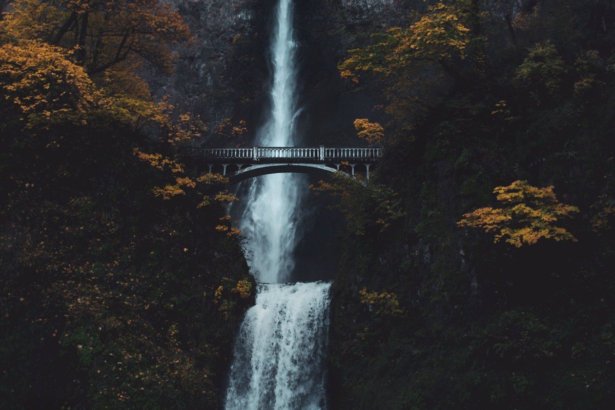 Multnomah Falls Oregon at dawn, mist rising off the pool beneath the stone footbridge
