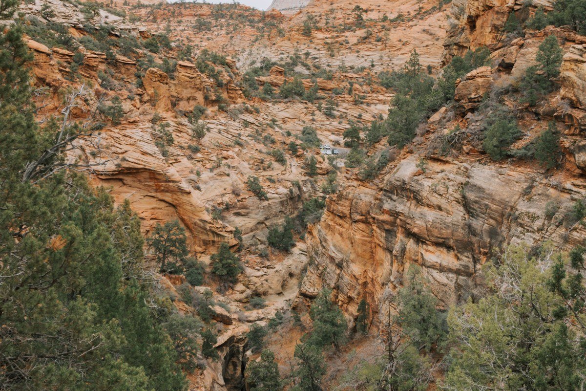 hiker rappelling into orange sandstone slot canyon in Zion National Park Utah