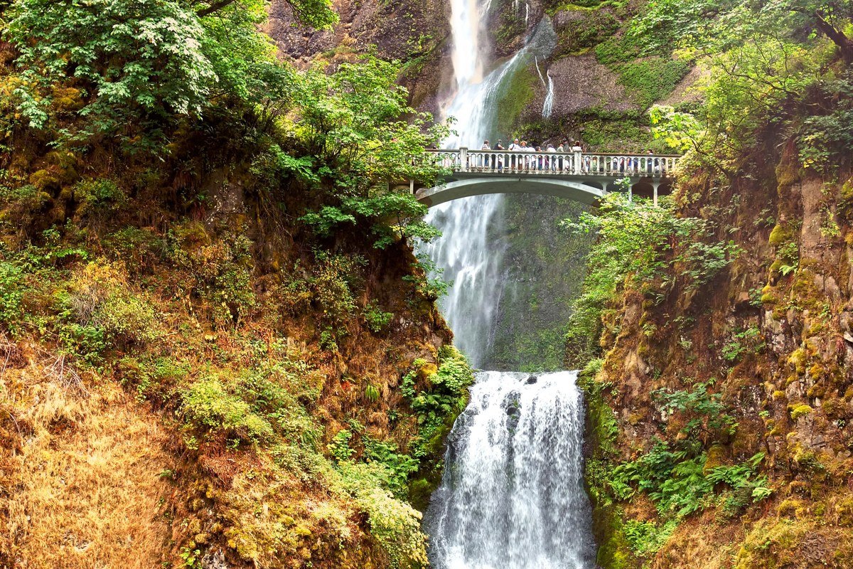 Multnomah Falls Oregon with mist rising from the base and moss-covered rock walls