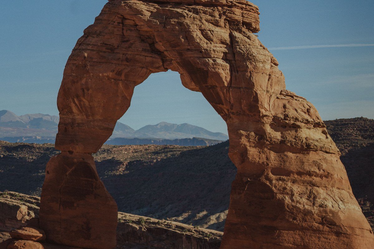 Delicate Arch glowing red at sunset with La Sal Mountains Utah