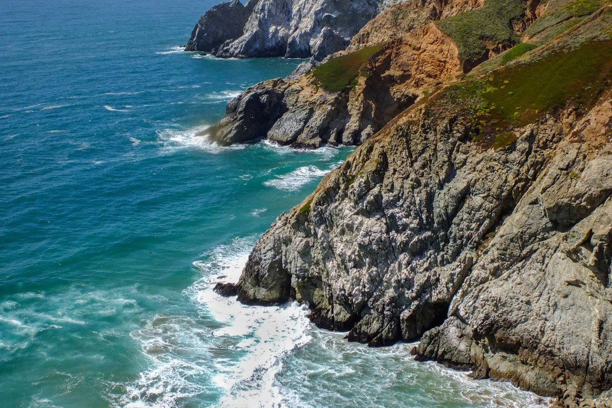 Point Sur lighthouse perched on volcanic rock promontory above crashing Pacific surf, California