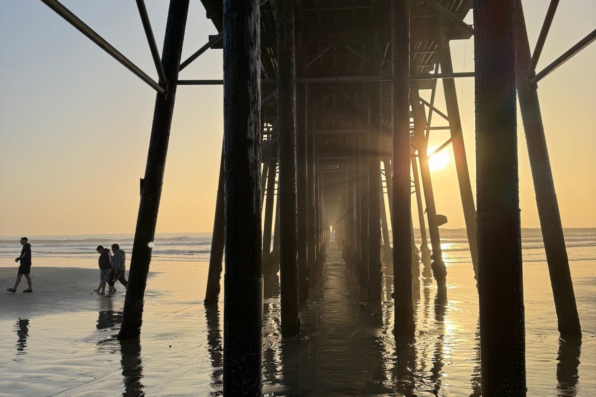 Cayucos California wooden pier with surfers at golden hour