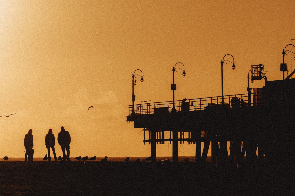 Ventura California pier at sunset with surfers in silhouette