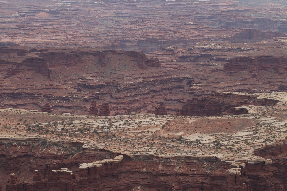 Mesa Arch Canyonlands sunrise with sun glowing through the sandstone arch and canyon layers visible beyond