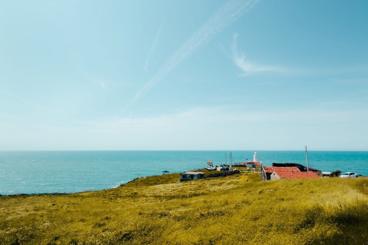 aerial view of Cape Cod coastline with dunes, blue water, and distant lighthouse