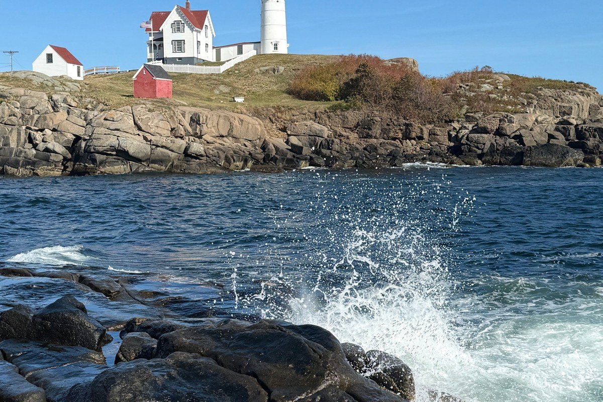 Portland Head Light Maine lighthouse wrapped in low morning fog with waves on rocks