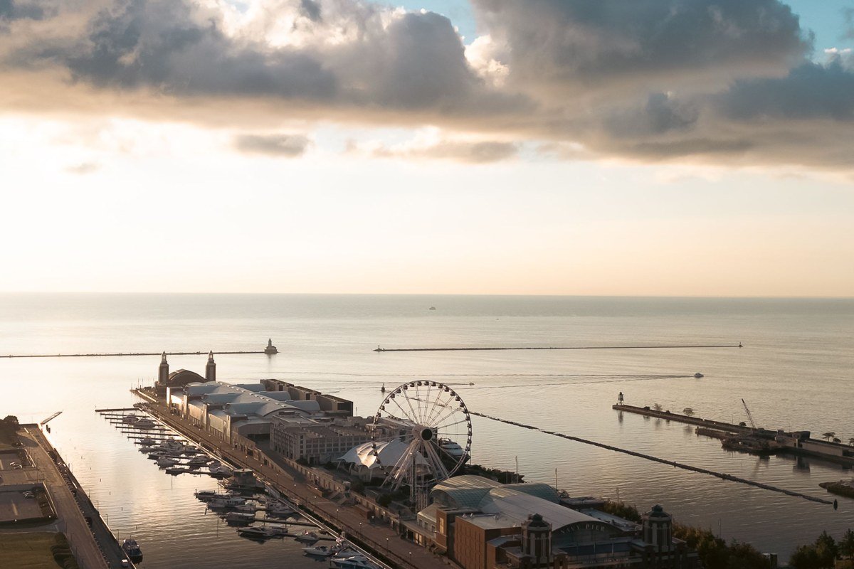 wide aerial view of Lake Michigan shoreline dunes and small lake town harbor at golden hour