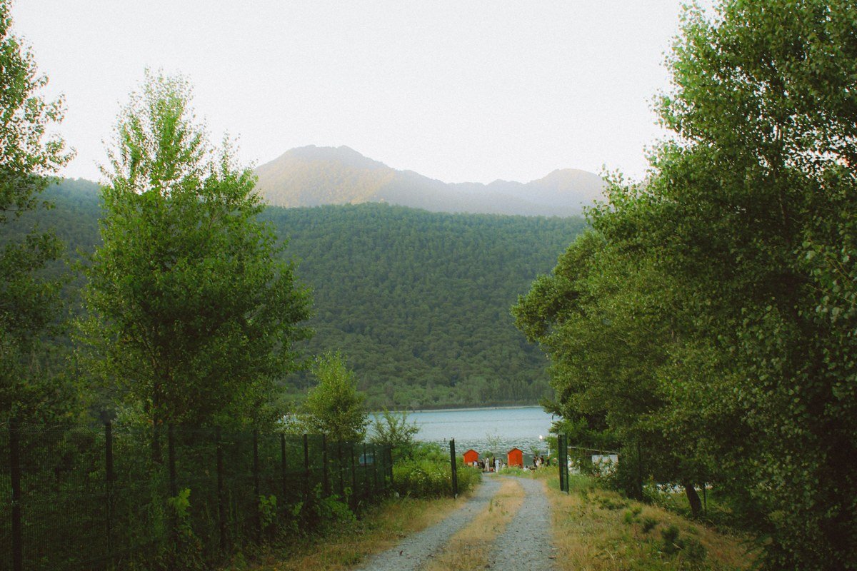 a wide gravel trail flanked by Sitka spruce, river visible through a gap in the fog
